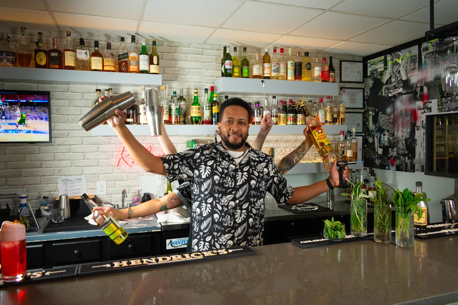 A bartender at the back bar, bottles stacked to the ceiling behind him