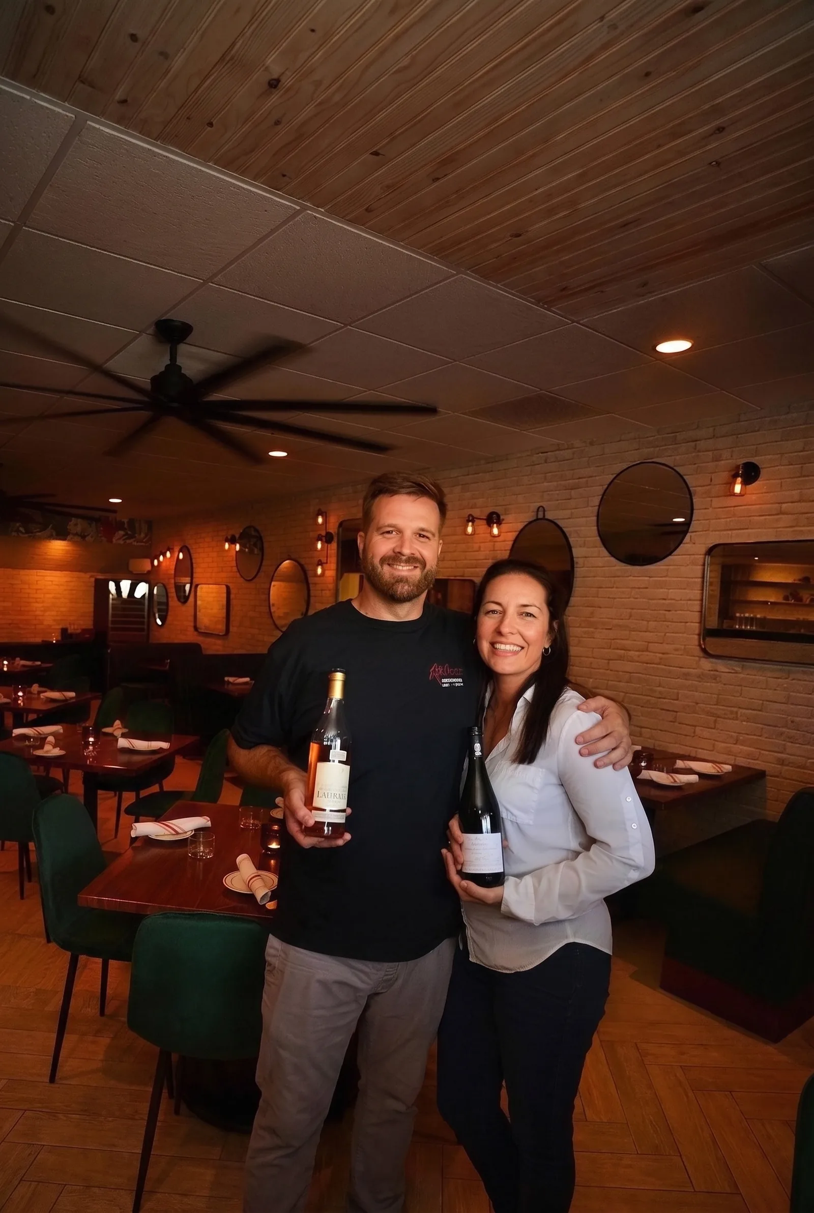 The owners in the dining room, each holding a bottle from the list