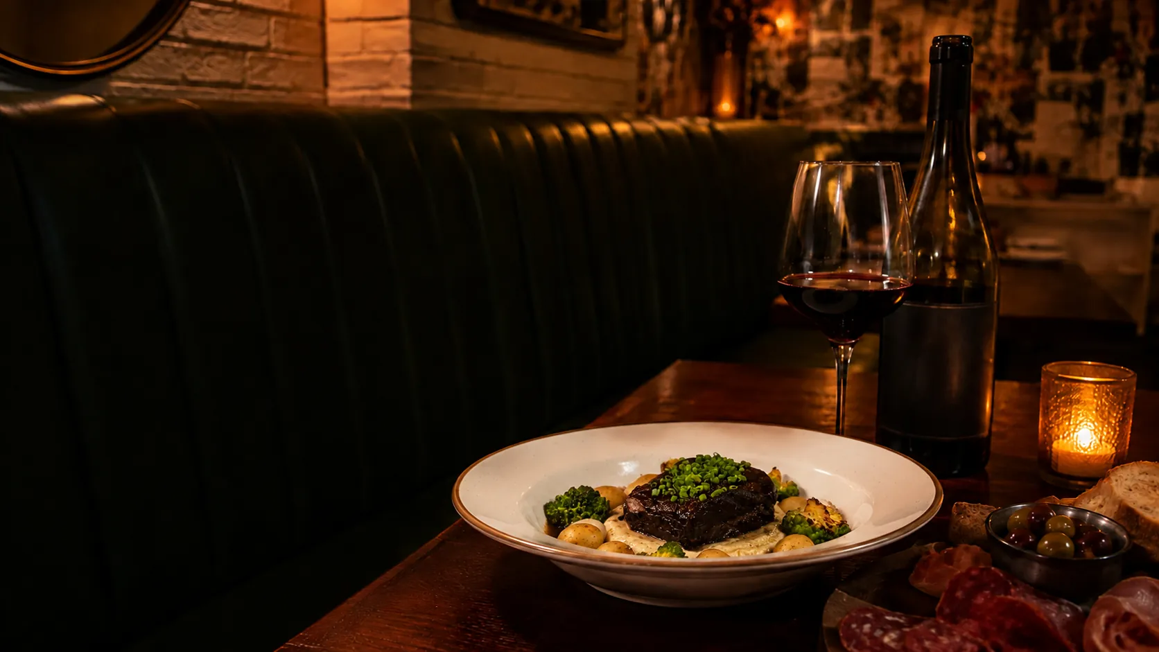 A braised short rib on gnocchi in a candlelit booth, with red wine and a charcuterie board alongside